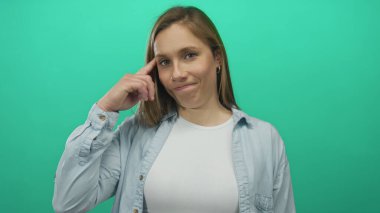 İzole edilmiş yeşil bir duvara karşı el ele düşünen bir kadın. Düşünceli bir ifade takınıyor. Günlük kıyafetler, sarı saçlar, gençlik tavırları ve gündelik tarzıyla..