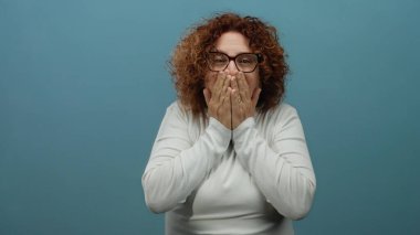 Kıvırcık saçlı, gözlerini kapayan, gülümseyen, gözlüklü, mavi arka planda yaşayan, soyutlanmış, orta yaşlı İspanyol asıllı bir kadın..