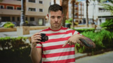 Dövmeli genç adam elinde kamera canlı şehir caddesini canlı binalarla gösteriyor.