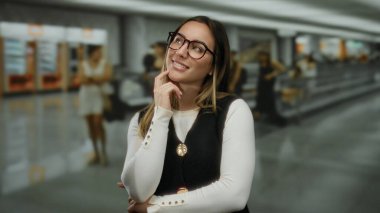 Havaalanı terminalinde güvenle gülümseyen genç bir kadın bulanık gezginler ve modern içiyle profesyonel ve hayat dolu bir atmosfer yaratıyor..