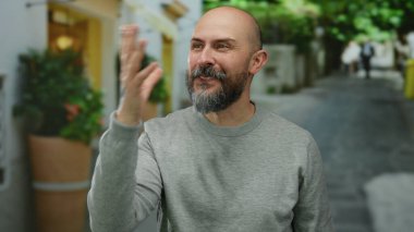 Sakallı ve dövmeli, şehir dışında gri süveter giyen, mutluluğu ifade eden bir adam..