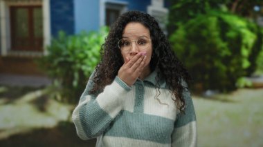 Gözlüklü kadın, gün ışığında çizgili süveter giyip arka planda ağaçlar olan sokakta şaşırdı. Meraklı ve etkileyici İspanyol kadın tepkileri sergiliyor..