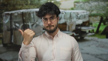 Güneşli bir günde dışarıda el kol hareketleri yapan İspanyol bir adam. Arka planda bulanık bir park. Düşünceli, analitik, düşünceli bir ifade.