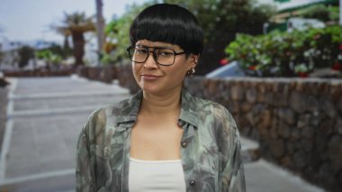 Dışarıdaki kadın gün ışığında yeşil ve taş duvarları olan bir şehir caddesinde kargaşa yaratıyor..