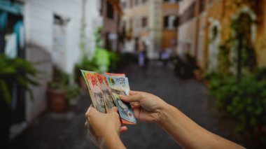Kentsel caddede Avustralya doları tutan adam, şehir ortamında döviz değişimi sergiliyor, iş ve finans konularını ön plana çıkarıyor.