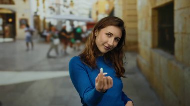 Kadın jestleri, sokak ortasında, açık havada, mavi süveter giyerek, şehir manzarası arka planında, duyguları ifade ederek, canlı sahnede genç beyaz kadın....