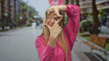 Tavşan kulaklı bir kadın canlı bir şehir caddesinde elleri ile neşeli bir çerçeve yapıyor. Canlı ve genç bir Paskalya havası yakalıyor..