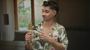 Gündelik gömlekli genç İspanyol adam, turizm ve turizm sergileyen bir otelde dondurmanın tadını çıkarıyor.