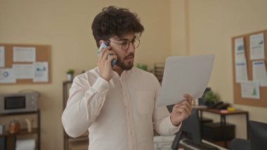 Ofisteki sakallı genç İspanyol adam akıllı telefondan konuşuyor ve içeride ciddi konuşmalar yapıyor..