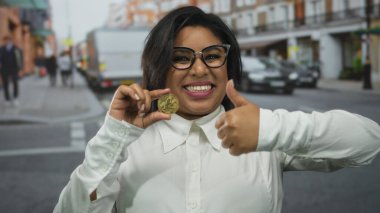 Şehir caddesinde litekoin tutan gülümseyen bir kadın dışarıda kripto para biriminin coşkusunu temsil eden bir onay veriyor..