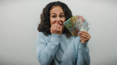 Orta yaşlı bir kadın, Avustralya dolarlarını gergin bir şekilde arka planda tutuyor. Duygusal bir mali endişe ve belirsizlik anını yakalıyor..