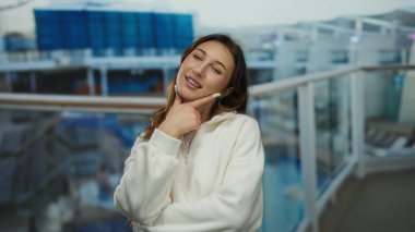 Düşünceli bir pozla bir yolcu gemisinde gülümseyen kadın, açık hava manzarasını seyrederken açık hava manzarasının keyfini çıkarıyor..