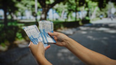 Şili pesolarını elinde tutan adam, açık bir şehir caddesinde, kentsel finans, yatırım ve uluslararası para birimi dinamiklerini vurguluyor..