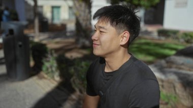 Güneşli bir günde gülümseyen genç bir adam, şehir ortamında pozitif bir şehir atmosferini yansıtırken yakalandı..