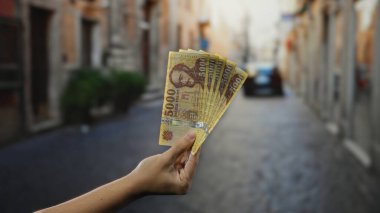 Açık bir şehir caddesinde elinde Macar banknotları tutan adam döviz kurunu veya şehir ortamında ekonomik konsepti sergiliyor..
