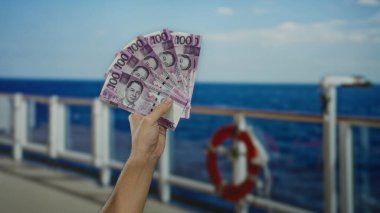 Deniz manzaralı bir yolcu gemisinde Filipinli pesolar tutan bir adam açık hava seyahati ve finans kavramını sergiliyor..
