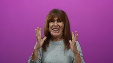 Hispanik son sınıf öğrencisi kadın canlı pembe bir arka plana karşı ellerini kaldırarak hayal kırıklığını dile getiriyor, duygularını ve yoğunluğunu izole bir ortamda aktarıyor..