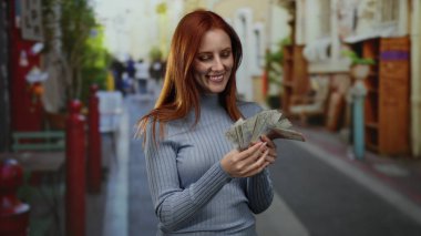 Canlı bir şehir caddesinde elinde İsveç banknotları tutan, neşeli bir ifade sergileyen ve açık bir şehir ortamında para birimini ön plana çıkaran bir kadın..