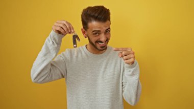 Genç İspanyol bir adam gülümseyip, parlak sarı bir arka plana karşı tuşları işaret ediyor..