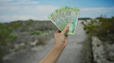 Açık hava parkında elinde Rus rublesi olan bir adam mali işlemleri ve döviz kurunu temsil eden bulanık doğal bir geçmişe karşı banknotlar sergiliyor..