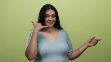 Sarı arka planda el kol hareketi yapan mavi gömlekli bir kadın bana işaret verirken gülümsüyor..