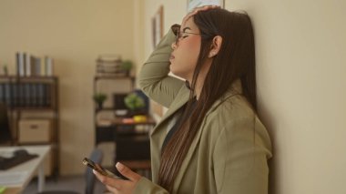 Ofiste stresli görünen bir kadın telefonu tutuyor. Genç Latin asıllı profesyonel. Kapalı bir iş yerinde tepeden tırnağa tutuyorlar..