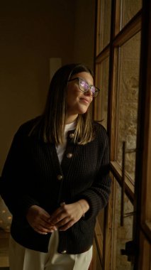 Akdeniz 'de bir evde duran bir kadın büyük bir pencereden dışarı bakıyor. İçerideki huzurlu ve rahat havayı yansıtıyor..