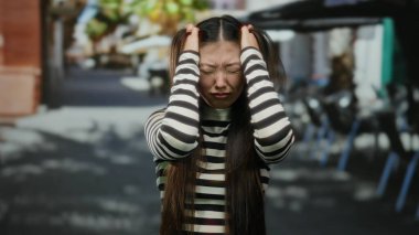 Şehir caddesindeki terasta duran kadın gün boyunca şehir merkezinde stres ve tefekkür içinde duygularını kapalı gözler ve çizgili gömlekle ifade ediyor..
