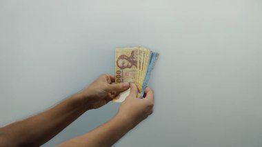 İzole edilmiş beyaz arkaplan duvarı üzerinde Macar forint banknotları tutan adam para yönetimi ve finansal konsept gösteriyor..