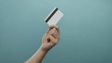 Elinde mavi bir arka planda kredi kartı tutan adam, izole ve modern bir ortamda finans, ödeme ve teknolojiyi sembolize ediyor..