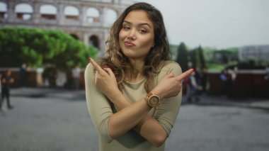 İspanyol kadın kollarını kavuşturuyor ve kolezyum binasında her iki tarafı işaret ediyor; karışıklık ikilemi.