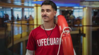 Modern kapalı otel ortamında kendine güveni olan genç İspanyol cankurtaranın elinde şamandıra var.