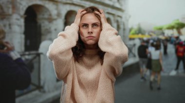 Roma Kolezyumu 'nun dışındaki kadın yoğun şehirde stresli görünüyor. Parlak bir günde kazak giyiyor..