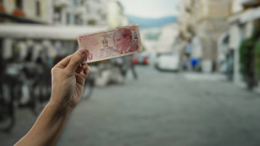 Şehir caddesinde elinde Türk lirası banknotları olan bir adam açık hava geçmişiyle şehir hayatını ve ekonomik değişimi yakalıyor..