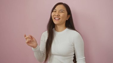 İzole edilmiş pembe bir arka plana güvenerek gülümseyen bir kadın güzellik ve tarz sergiliyor..