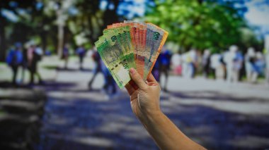 El ele tutuşarak Güney Afrika rand banknotları ile şehir sokakları ve arka planda insanlar, bir açık şehir ortamında para özünü yakalamak.