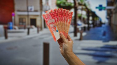 Bir şehir caddesinde Filipin pesolarını elinde tutan adamın eli, şehir ortamında finans, para, iş ve yatırım fırsatlarını temsil ediyor.