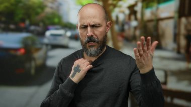 Şehir sokağında sakallı bir adam yaz sıcağında sıcak ve rahatsız görünüyor..