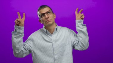 Gözlüklü, parlak mor arka planda tırnak işaretleri olan, düşünceli bir duruşta, çizgili bir gömlek giyen, beyaz bir adam..