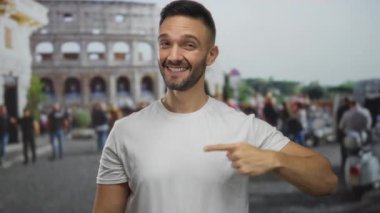 İspanyol genç adam kendini işaret ediyor ve Roma tarihi kolezyumunda bir sevinç anı yakalıyor ve simgesel İtalyan simgesi ile bağlantı kuruyor..