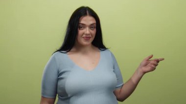 Sarı arka planda el kol hareketi yapan mavi gömlekli bir kadın bana işaret verirken gülümsüyor..