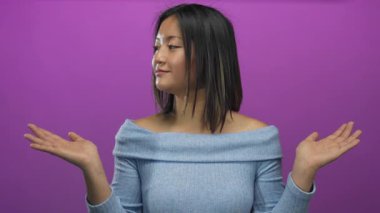 Mor arka planda jest yapan mavi gömlekli kadın neşeli ve anlamlı görünüyor.