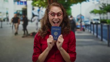 Kadın heyecanlı bir şekilde şehir caddesinde Kore pasaportu taşıyor, kırmızı tişört giyiyor, açık ağızlı ve günlük sokak atmosferiyle mutluluğu ifade ediyor..