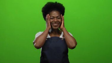 Önlük giymiş gülümseyen kadın canlı yeşil arka plana karşı duruyor. Güven ve neşe saçıyor. Mutfak ya da profesyonel temalar için mükemmel..