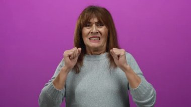 Hispanik son sınıf öğrencisi kadın canlı pembe bir arka plana karşı ellerini kaldırarak hayal kırıklığını dile getiriyor, duygularını ve yoğunluğunu izole bir ortamda aktarıyor..