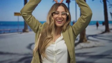 İş kadını, deniz kenarında elleri ile baş üstünde kalp hareketi oluşturur; aşk sevinci sevgiyi ısıtır.