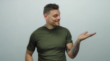 Beyaz arka planda avuçlarını gösteren dövmeleri olan genç İspanyol bir adam. Tarafsız bir duvarın üzerinden izole edilmiş tişört giyerken gülümsüyor ve cana yakın görünüyor..