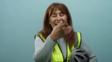 Üst düzey İspanyol kadın, elinde mavi duvar arkası kaskla neşeyle gülüyor, güvenlik bağlamında mutluluk ve mizah iletiyor..