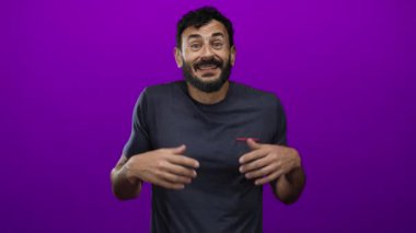 Sakallı İspanyol bir adam canlı mor bir arka plana karşı omuz silkiyor. Karışıklık ve belirsizlik taşıyor. Stüdyo ortamında sorgulama jesti yaparak ellerini kaldırıyor..
