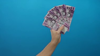 Beyaz adamın, Filipin pesolarını mavi bir duvara dayayıp, canlı ve izole bir ortamda servetini ve para birimini sergilemesi, finansal işlemleri vurgulaması,.